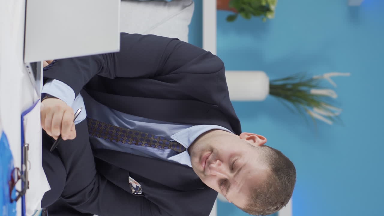 홈 오피스 직원 남자가 우울증을  ⁇ 고 있는 수직 비디오.