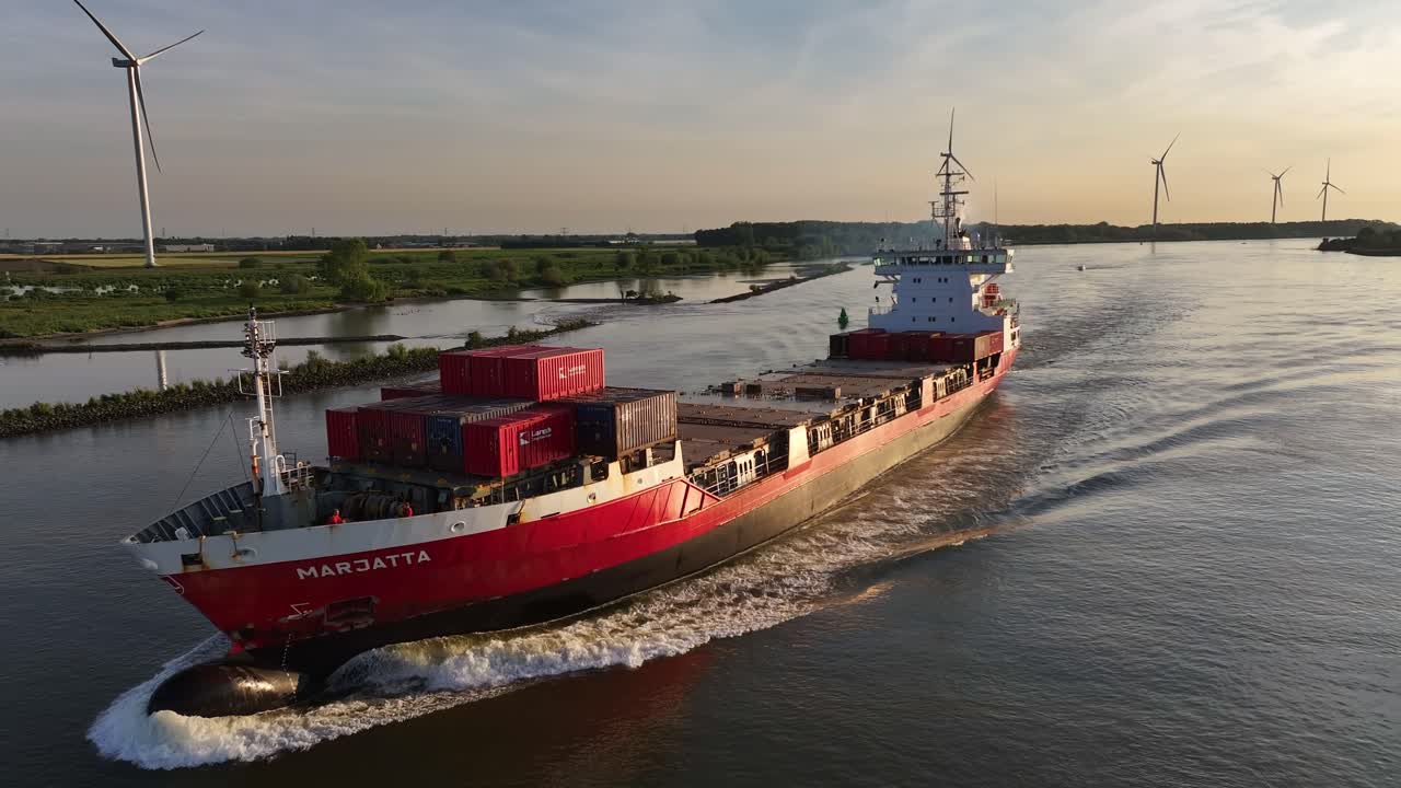 Red Cargo Ship MARJATTA on a Waterway with Wind Turbines