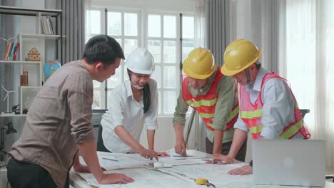 three asian engineers with helmets presenting work on the tablet to a man at the office