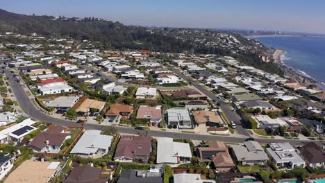 wide reverse aerial pullback shot of a malibu bluffs housing community along the coast in california