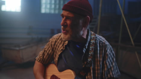 elderly man playing acoustic guitar in warehouse