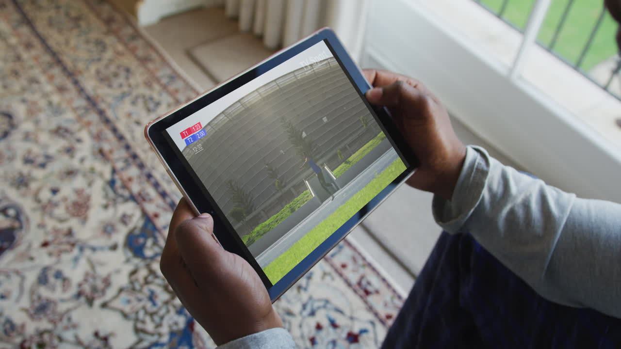 Composite of man sitting at home, watching athletics javelin event on tablet