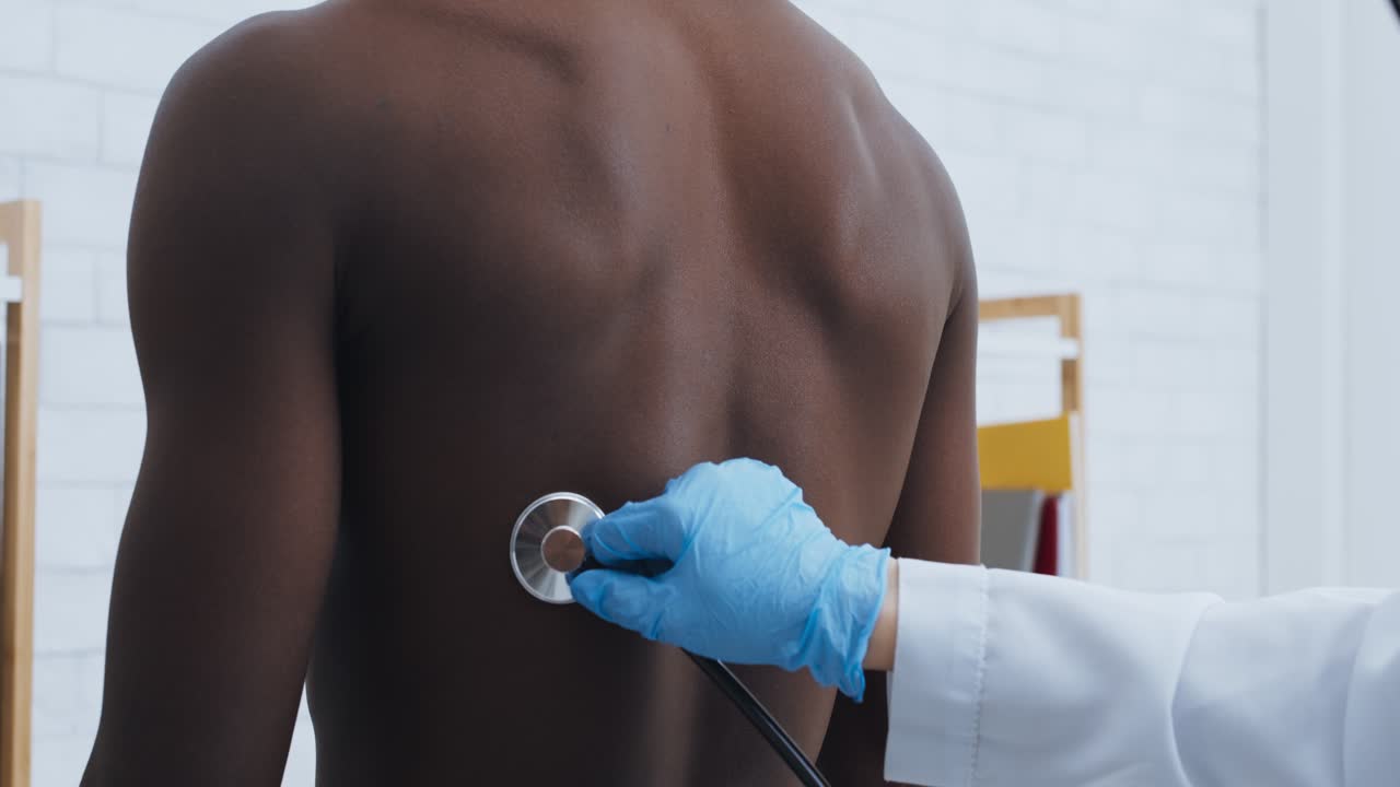 Doctor examining patient's back with stethoscope