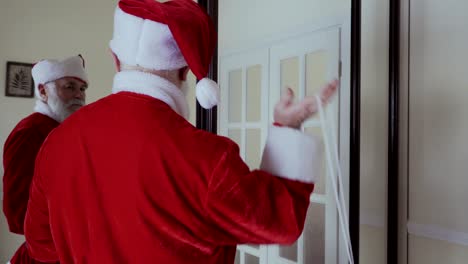 santa claus usa su sombrero rojo, abre la puerta y sale.