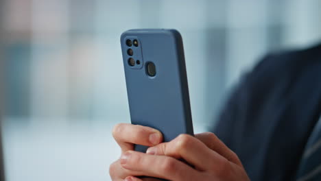 smiling businessman messaging cellphone in office closeup. manager hands texting