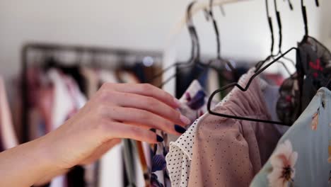 el primer plano de la mano de la mujer elige la ropa en una percha en la tienda