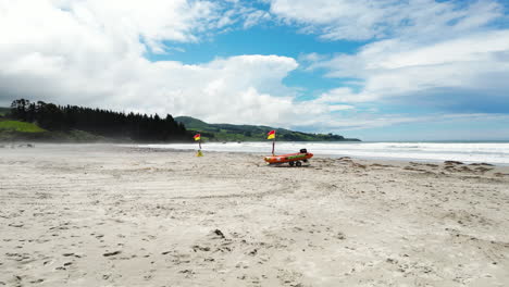 Aerial-flying-towards-surf-lifesaving-tender-boat-on-deserted-beach,-New-Zealand