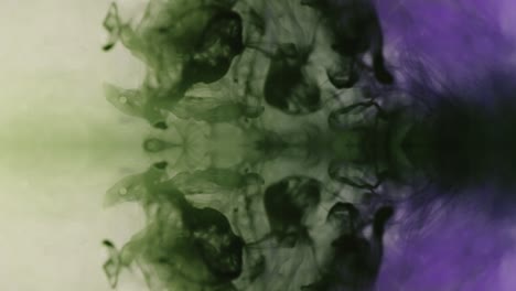 vertical view of ink visuals with green and purple color blending under water