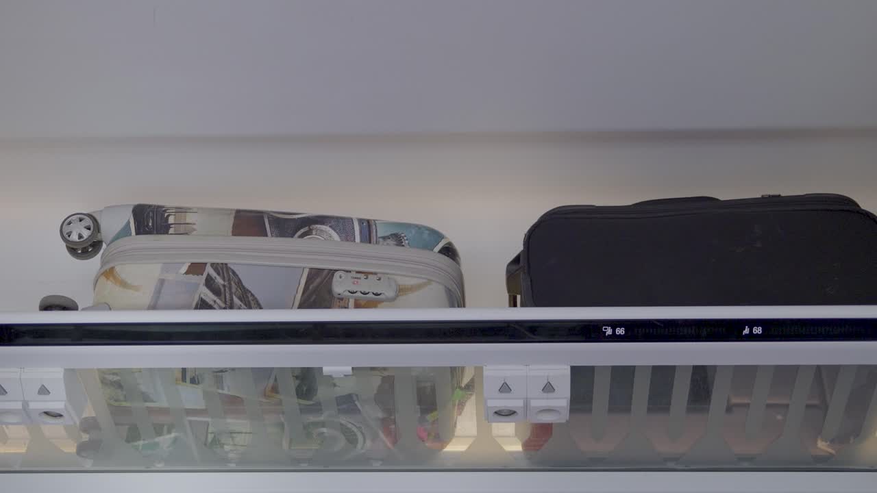 Inside a train, two suitcases are stored on a shelf, showing travel and transport
