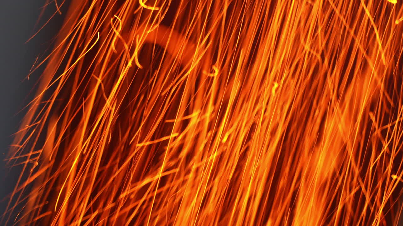 Quick orange scintilla flying vertically down. Hot particles at a fast speed at black background. Close up.