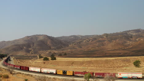 tren parado en las vías debajo de las colinas quemadas por los incendios forestales - vista aérea