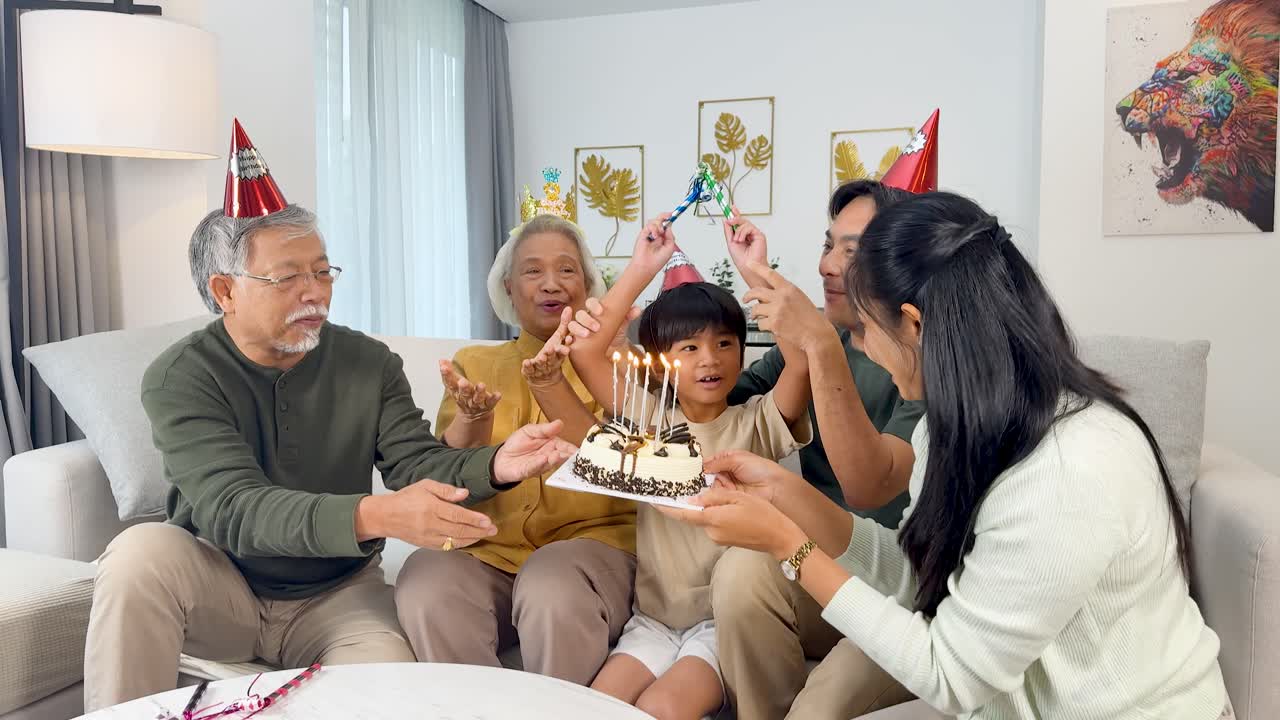 Three generations gather in a bright living room to light candles and celebrate a birthday