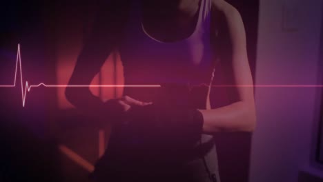 Animation-of-glowing-pink-heart-rate-monitor,-over-sportswoman-wrapping-hand-for-boxing