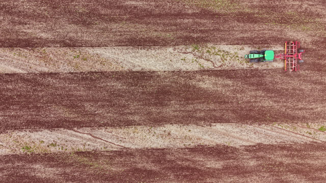 Un agricoltore usa il trattore per preparare il campo per la semina in un terreno agricolo di giorno, in una zona rurale.