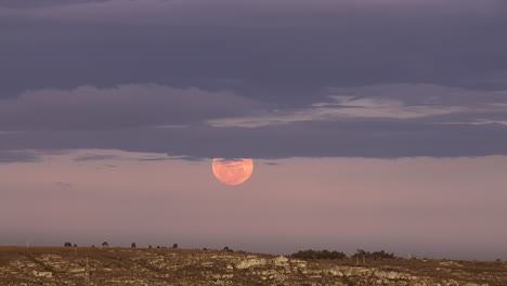 ascenso de una luna roja brillante con nubes sobre el horizonte de la tierra