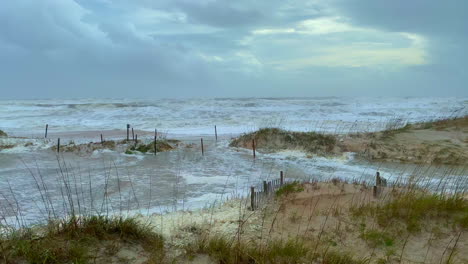 hurricane storm force waves crashing onto shore flooding beach and sand dunes