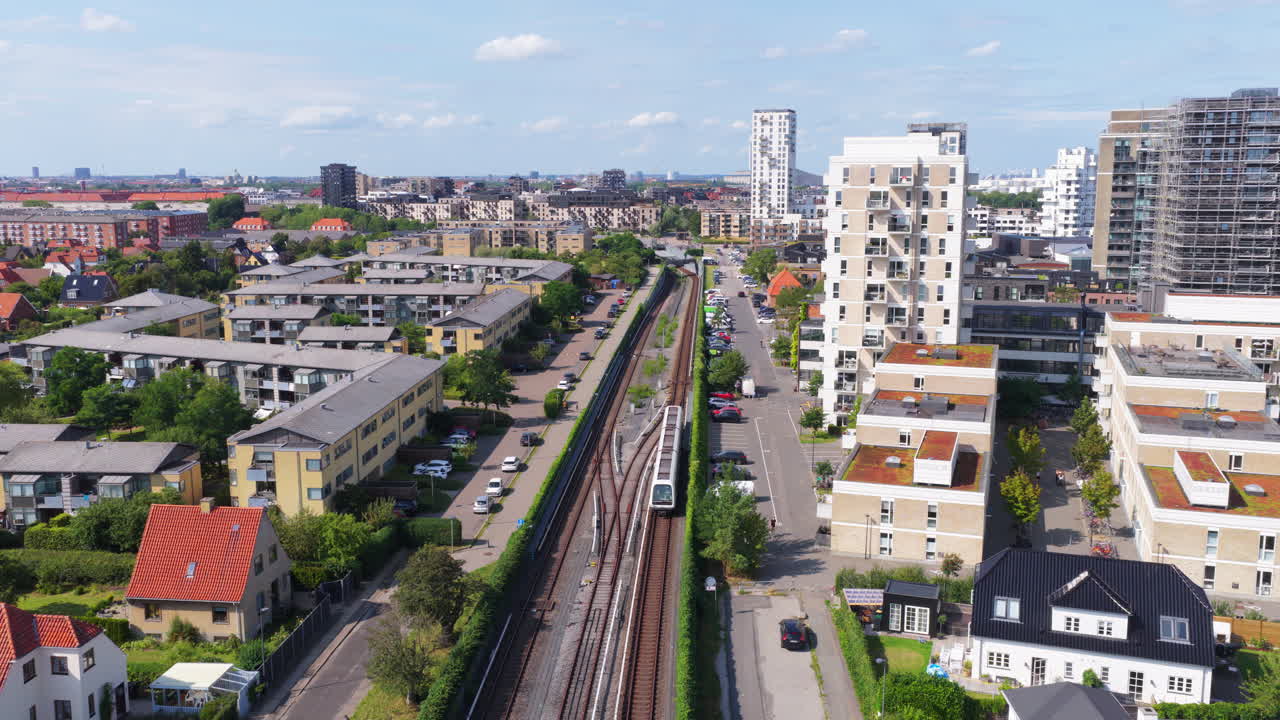 Aerial drone view of Copenhagen Metro line, with a train traveling through residential neighborhoods near Amager in Denmark