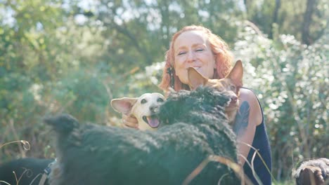 a woman affectionately hugs her dogs in a natural outdoor setting