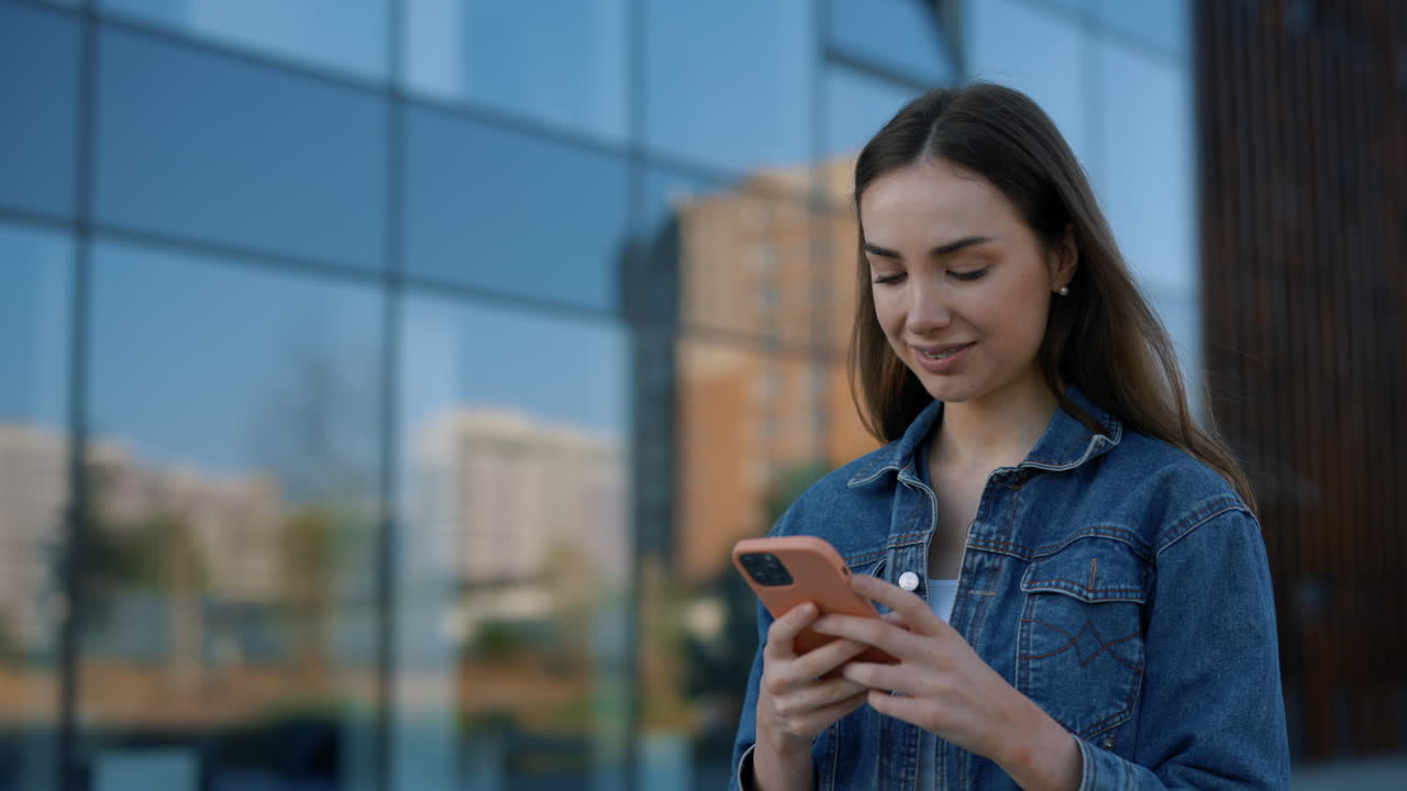 Woman using a smartphone in front of a modern building