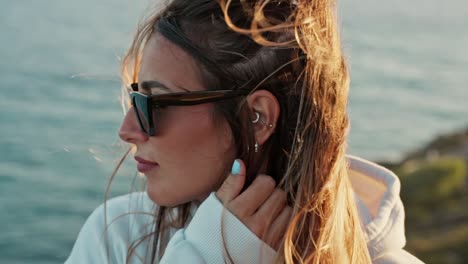 Un-Retrato-De-Cerca-De-Una-Mujer-Con-Gafas-De-Sol-Se-Mete-El-Pelo-Detrás-De-La-Oreja-Con-La-Mano