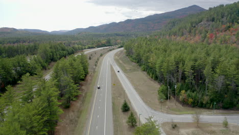 drone shot of cars driving along a scenic highway in a forest in upstate new york