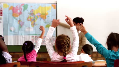 young pupils raising hands during geography lesson in classroom