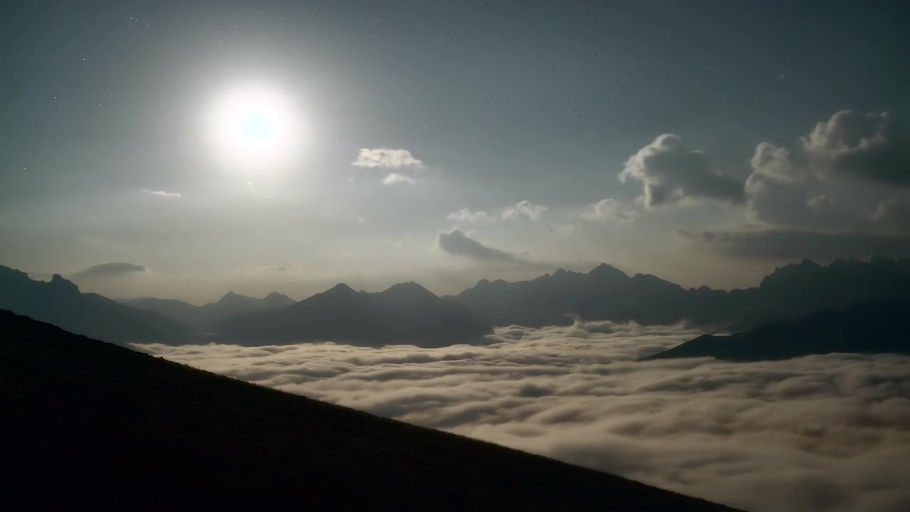 Volle maan schijnend boven bergtoppen boven een wolkenzee