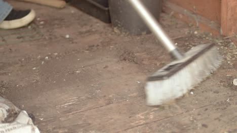 homeowner sweeping dirt and  dust in timber shed