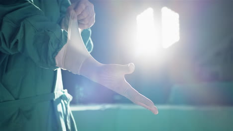 Midsection-of-caucasian-male-surgeon-wearing-medical-gloves-in-operating-theatre,-slow-motion