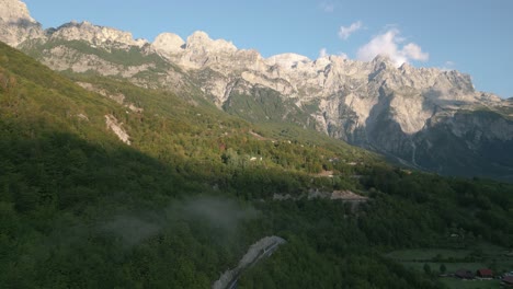 mountain road winding through lush green valleys with rugged albanian alps in the background