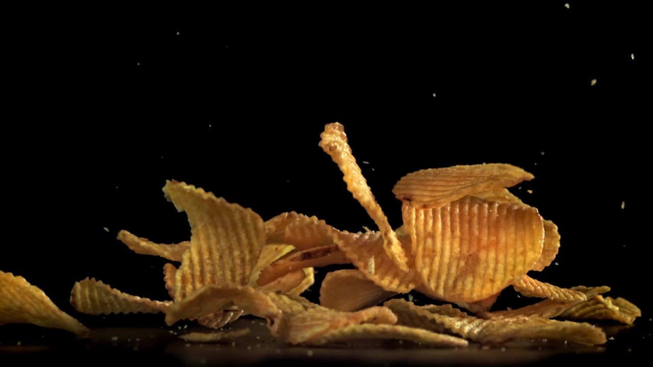 Patatine fritte croccanti e ondulate che cadono al rallentatore