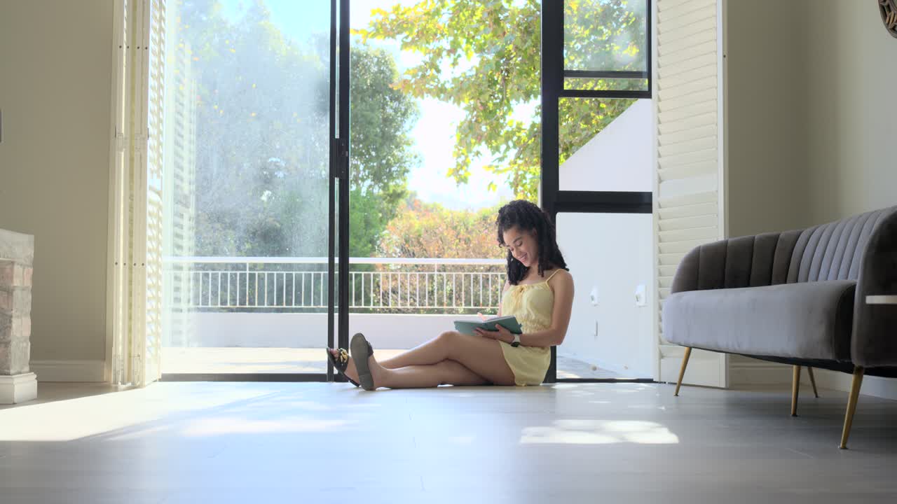 縦型動画：黄色いドレスを着た女性、引き戸のそばに座って本を読み、ページをめくり、ちらりと見る。