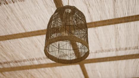 woven bamboo lantern hanging from a bamboo pergola ceiling, creating a rustic and natural ambiance