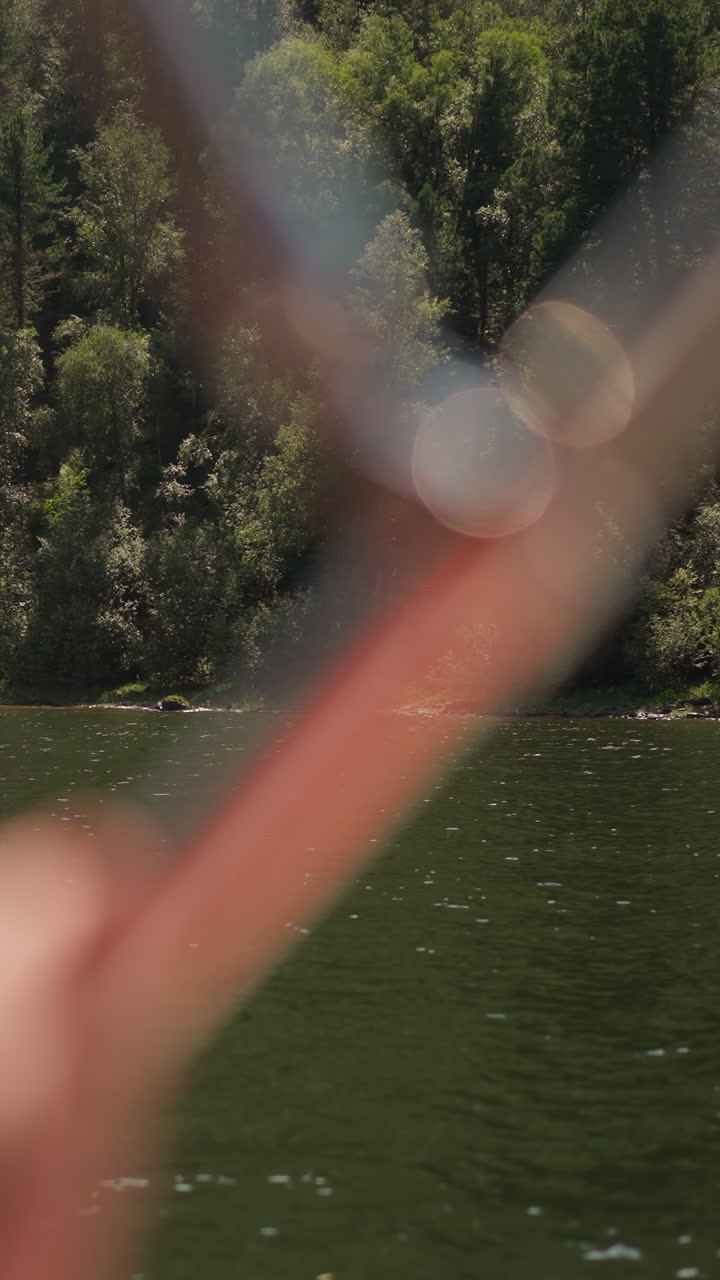 Wild forest on sloped coast and yacht with tourist on summer day. Travelling by vessel past wood hills on lake bank. River journey at nature resort