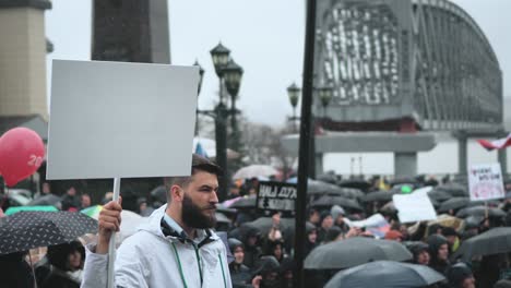 bearded man on rally holding blank ads board. empty chromakey panel for text.