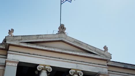 greek flag waving proudly above athens university building