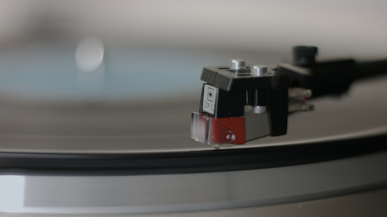 UHD footage captures the stylus gently dropping onto a spinning vinyl record on a vintage turntable, evoking rich analog sound and nostalgic charm as the music begins to play.