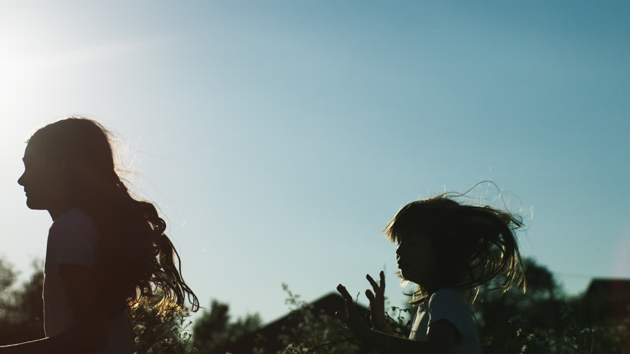 해가 지는 동안 에서 달리는 두 소녀의 실루