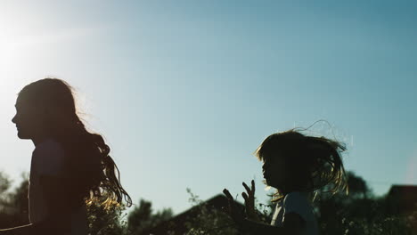 silhouette of two girls running in a field at sunset