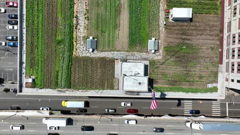 aerial top down shot of agricultural field on rooftop in new york city and traffic on road in summer - rise overhead shot