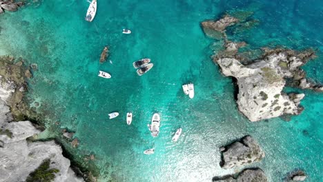 drone captures a high altitude shot of the crystal blue sea off the italian island of tremiti, where several boats are sailing