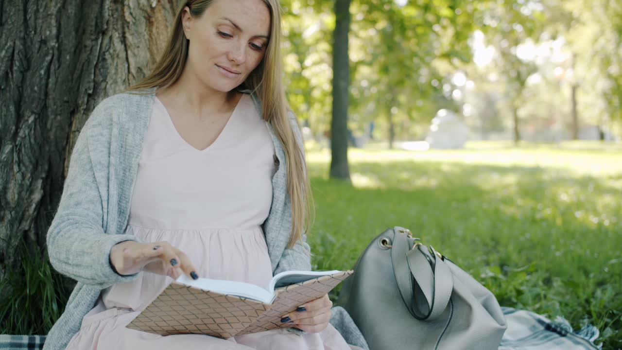 Donna incinta che legge un libro in un parco