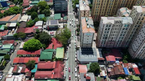 aerial flyover of a bustling street along residential houses and condominium buildings at west crame, san juan city, philippines during daytime.
