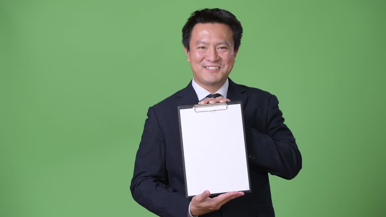 Mature Japanese businessman against green background