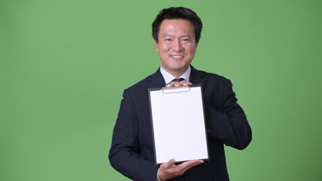 mature japanese businessman against green background