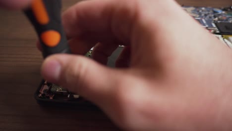 man unscrews and removes hard drive from laptop using hands and screwdriver