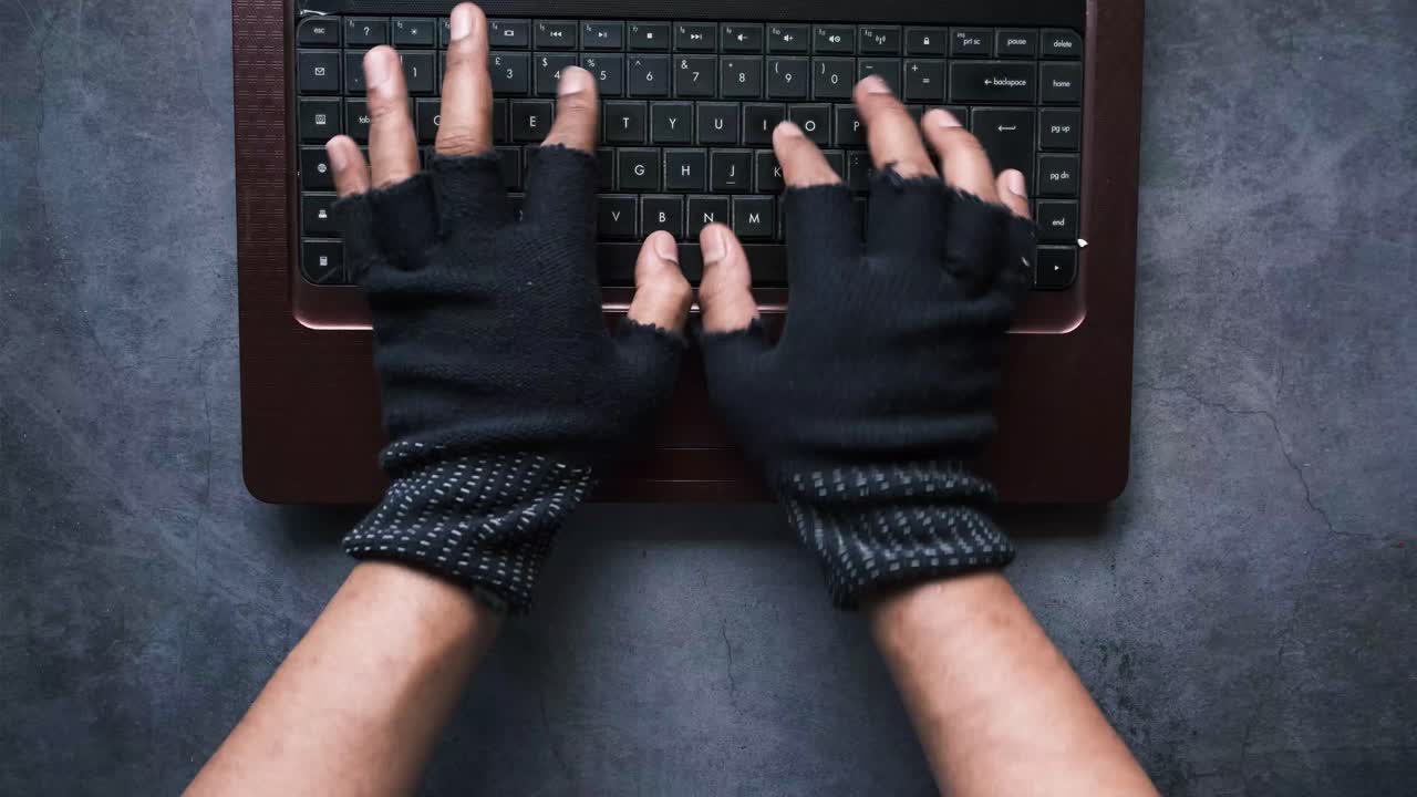 Hands in Gloves Typing on Laptop Keyboard