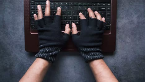 hands in gloves typing on laptop keyboard