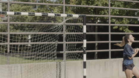 slow motion of focused female goalkeeper hitting ball with hand