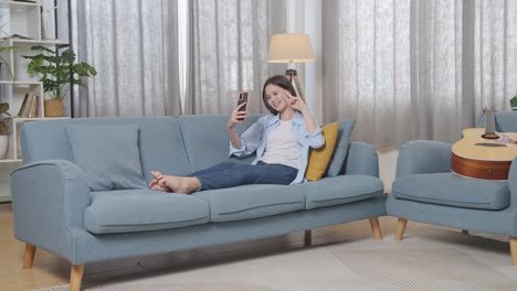 teenage girl using smartphone on sofa in living room